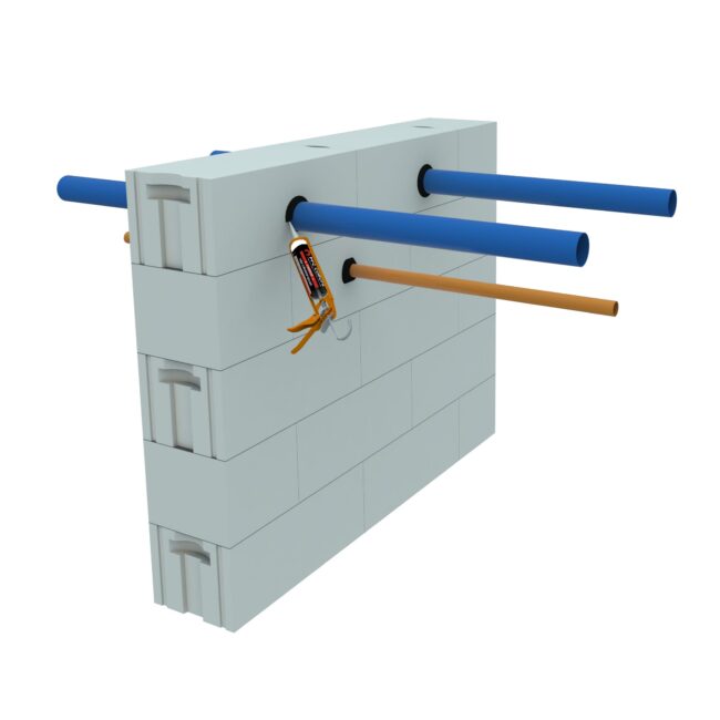 Three blue and one brown pipe pass through holes in a white block wall; one hole is being sealed with caulk.