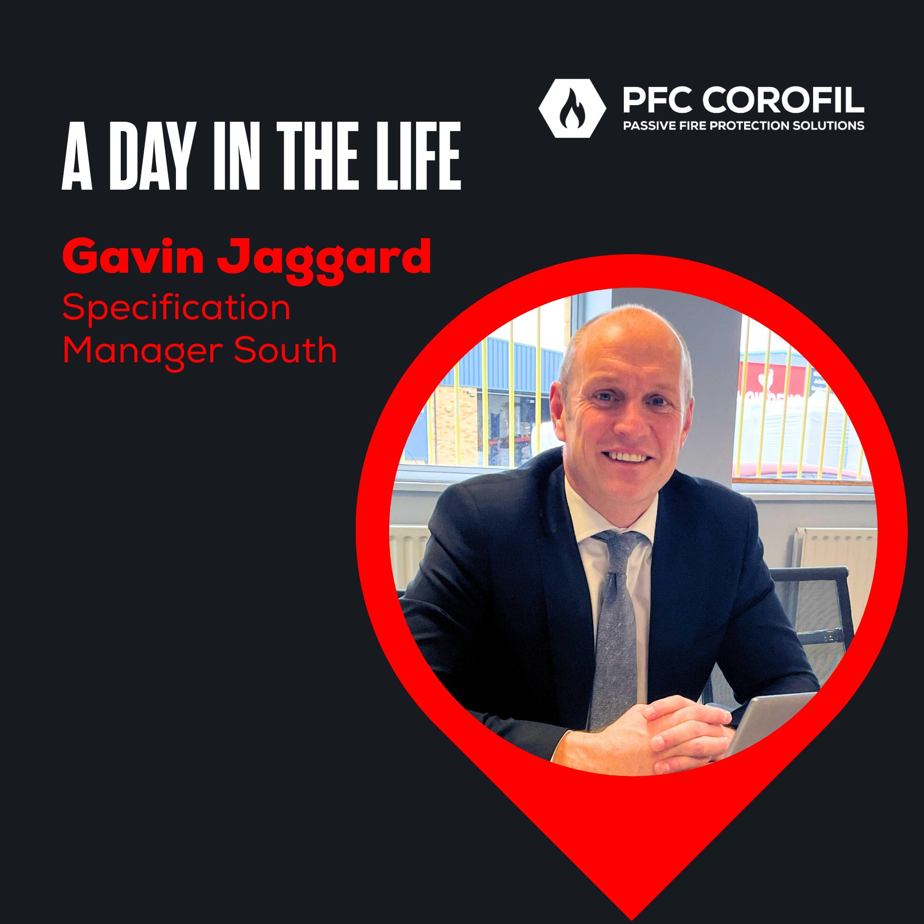 Gavin Jaggard, Specification Manager South, smiles at his desk in a suit.