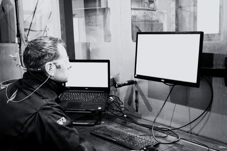 Man in safety glasses fire rated testing at desk with computer and laptop.